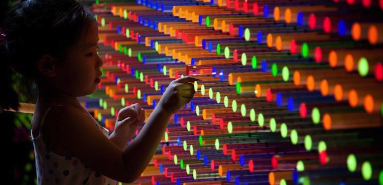 Girl pulling colorful tubes from the wall
